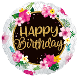 A round foil balloon with a white scalloped edge, featuring a dark brown center with glittery gold text that reads 'Happy Birthday' and surrounded by tropical pink, yellow, and white flowers with green leaves.
