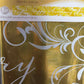 Gold metallic banner with 'Happy Anniversary' text and decorative patterns on packaging.